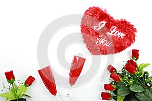 Valentine`s Day concept. Heart shaped pillow with red champagne glass and red roses isolated on white background.
