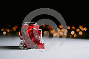 Valentine`s day concept. jar with small hearts red  on a light background with bokeh