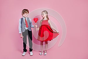 Valentine& x27;s day concept. Little boy and girl with candy red lollipop in heart shape. Beautiful children eat sweets.