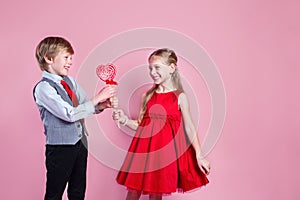 Valentine's day concept. Little boy and girl with candy red lollipop in heart shape. Beautiful children eat sweets.
