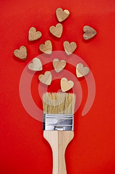 Valentine`s Day concept . Paint brush drawing with wooden hearts on a red background