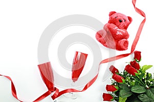 Valentine`s Day concept. Red champagne glass with red teddy bear and red roses with red ribbon on isolated on white background.