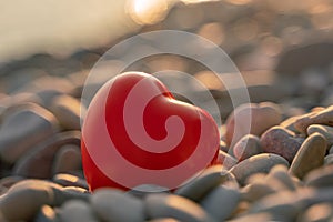 Valentine's Day concept. Red heart romantic love symbol on pebble beach at sunset with copy space. Template for