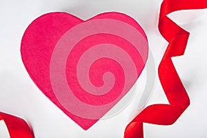 Valentine`s day concept. Red silk ribbon and heart on a white background