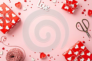 Valentine`s Day concept. Top view photo of gift boxes heart shaped candles inscription love spool of twine scissors and sprinkles