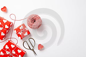 Valentine`s Day concept. Top view photo of gift boxes heart shaped candles spool of twine and scissors on isolated white