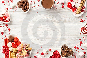 Valentine\'s Day concept. Top view photo of heart shaped crockery with chocolate jelly candies cookies and glass cup of hot