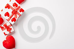 Valentine`s Day concept. Top view photo of present boxes with red ribbon bows and heart shaped fluffy pillows on isolated white