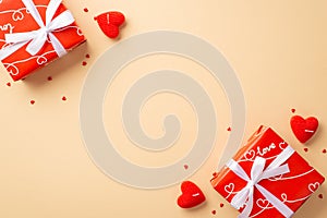 Valentine`s Day concept. Top view photo of red gift boxes heart shaped candles and sprinkles on isolated pastel beige background