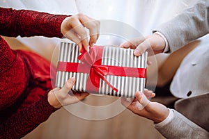 Valentine`s day concept. Top view of a woman opening a giftbox with red ribbon in hands. Loving couple give each other presents o