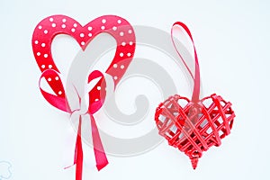 Valentine's day concept. Two red hearts. Wooden heart with white dots and a ribbon bow on a stick. Wicker heart with a