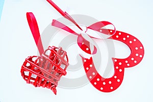 Valentine's day concept. Two red hearts. Wooden heart with white dots and a ribbon bow on a stick. Wicker heart with a