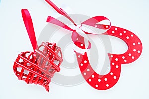 Valentine's day concept. Two red hearts. Wooden heart with white dots and a ribbon bow on a stick. Wicker heart with