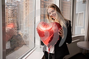 Valentine& x27;s day concept, woman with red balloon heart standing by the window, business lady in office celebrating