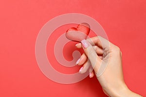 Valentine`s day concept. A young girl holds a heart in her hand on a red background. Copy space