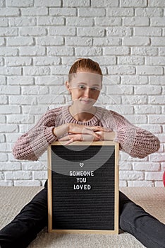 Young woman sitting behind the felt letter board with the words Someone You Loved