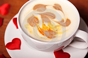 Valentine`s day. A Cup of cappuccino with a heart-shaped latte art on a wooden table. The concept of Declaration of love