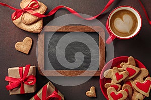 Valentine`s Day with a cup of coffee, a board, a heart-shaped cookie, a gift. Top view with copy space