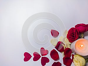 Valentine`s day decoration with scented candle and rose petals of red, yellow, white colors in white background