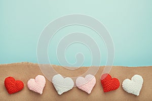 Valentine's day decorative background. Six handmade crochet hearts on on torn craft paper.