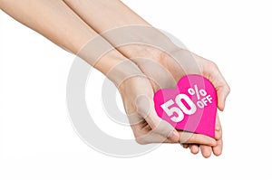 Valentine's Day discounts topic: Hand holding a card in the form of a pink heart with a discount of 50% on an isolated