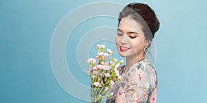 Valentine`s Day - Dreaming Voluptuous Young Woman with Bouquet of Flowers while standing against blue background