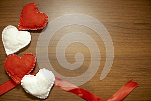 Valentine`s Day, February 14th. Red and white heart on a wooden background. With candles and a red silk ribbon