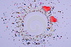 Valentine's day festive composition background. Wreath made of red hearts with multicolored confetti around on