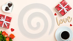 Valentine`s Day flatlay composition with gift boxes, roses, coffee cup and candy on pastel beige background. Flat lay, top view,