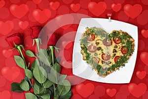 Valentine`s day food. Heart shaped pizza next to a red roses, on a red background, with bokeh of heart. Valentine`s day concept.