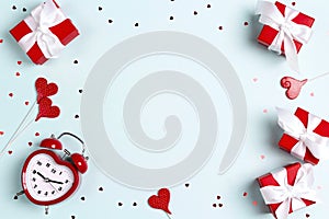 Valentine`s day frame with alarm clock, gift boxes and hearts on a blue background. Copy space