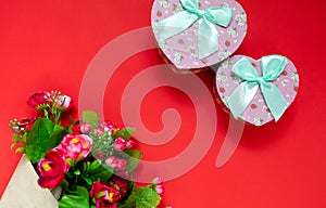 Valentine`s day gift for the second half, a bouquet of flowers, a romantic photo, a cardboard pink heart bow on a red background,