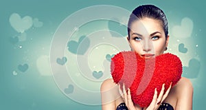 Valentine`s day. girl with heart shaped fluffy red pillow
