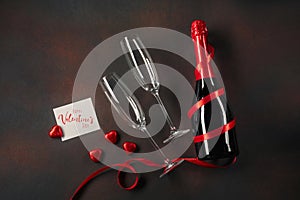 Valentine`s day greeting card with champagne glasses and candy hearts on stone background. Top view with space for your greetings