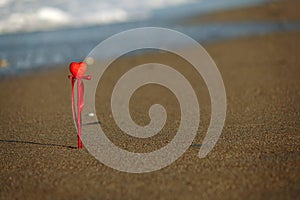 Valentine`s day greeting card concept, red heart on pristine sandy beach, honeymoon vacation background. symbol of love