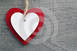 Valentine`s Day greeting card.Decorative red and white wooden hearts on a grey wooden background.