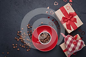 Valentine`s day greeting card. Gift box with red ribbon and cup with grains of aromatic coffee, heart figurines on black