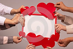 Valentine`s day greeting card. The hands of five girls hold felt hearts and a red frame. Mockup, copy space.