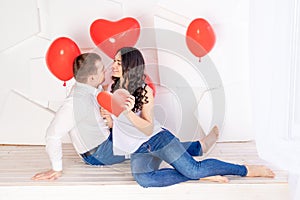 Valentine`s day, a guy with a beautiful girl look at each other with a loving look, which holds a big red heart