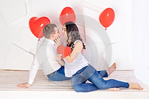 Valentine`s day, a guy with a beautiful girl look at each other with a loving look, which holds a big red heart