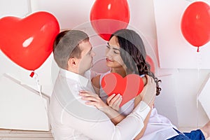 Valentine`s day, a guy with a beautiful girl look at each other with a loving look, which holds a big red heart