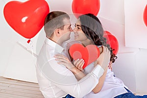 Valentine`s day, a guy with a beautiful girl look at each other with a loving look, which holds a big red heart