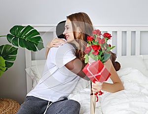 Valentine`s Day. happy couple with flowers in bed