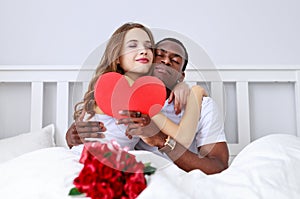 Valentine`s Day. happy couple with flowers in bed