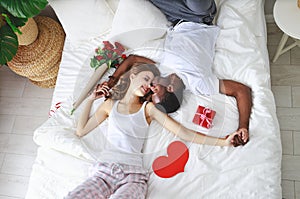 Valentine`s Day. happy couple with flowers in bed photo