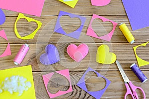 Valentine`s day hearts crafts. Colorful hearts gifts made of felt, felt scraps, scissors, thread on wooden table