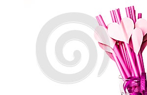 Valentine`s day holiday. bright pink drinking straws with hearts and a pink ribbon in a glass isolated on white