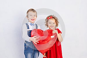 Valentine`s day kids. Boy and girl holding big red heart ball