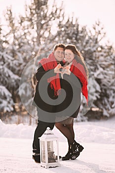 Valentine`s Day. loving young couple having a good time in winter snowy forest. Hands folded in heart