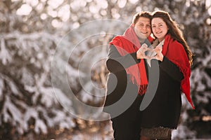 Valentine`s Day. loving young couple having a good time in winter snowy forest. Hands folded in heart